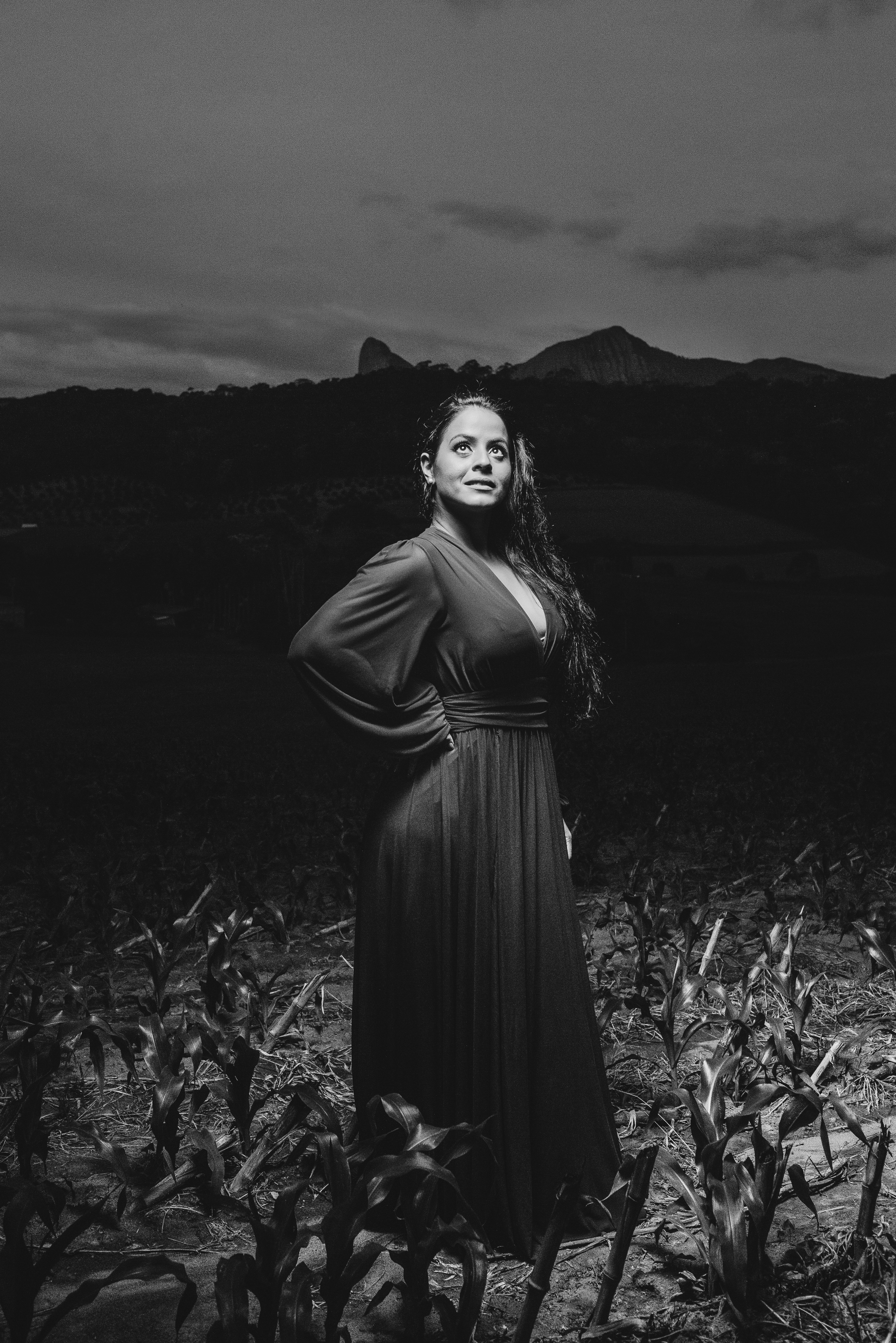 woman in black dress standing on grass field in grayscale photography